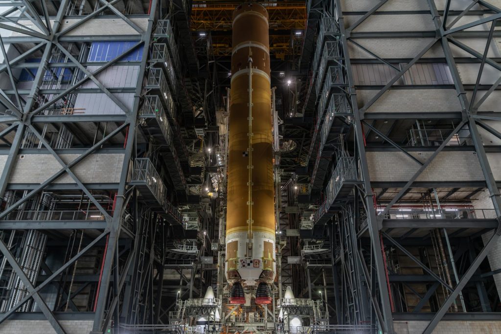 Etapa central anaranjada del cohete SLS de Artemis III, suspendida en posición vertical dentro del Edificio de Ensamblaje de Vehículos del Centro Espacial Kennedy.