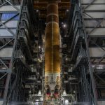 Etapa central anaranjada del cohete SLS de Artemis III, suspendida en posición vertical dentro del Edificio de Ensamblaje de Vehículos del Centro Espacial Kennedy.