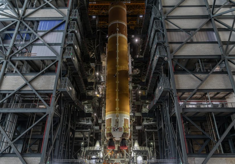 Etapa central anaranjada del cohete SLS de Artemis III, suspendida en posición vertical dentro del Edificio de Ensamblaje de Vehículos del Centro Espacial Kennedy.
