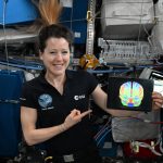 La astronauta Sophie Adenot sostiene una imagen de resonancia cerebral en la Estación Espacial Internacional.