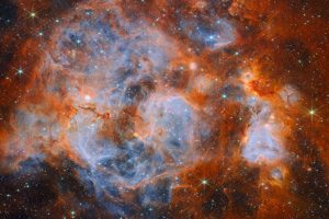 Imagen infrarroja de la nebulosa N159 captada por el telescopio James Webb, con nubes azuladas y anaranjadas y estrellas brillantes.