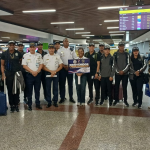 Delegación internacional reunida en un aeropuerto durante la recepción de equipos.