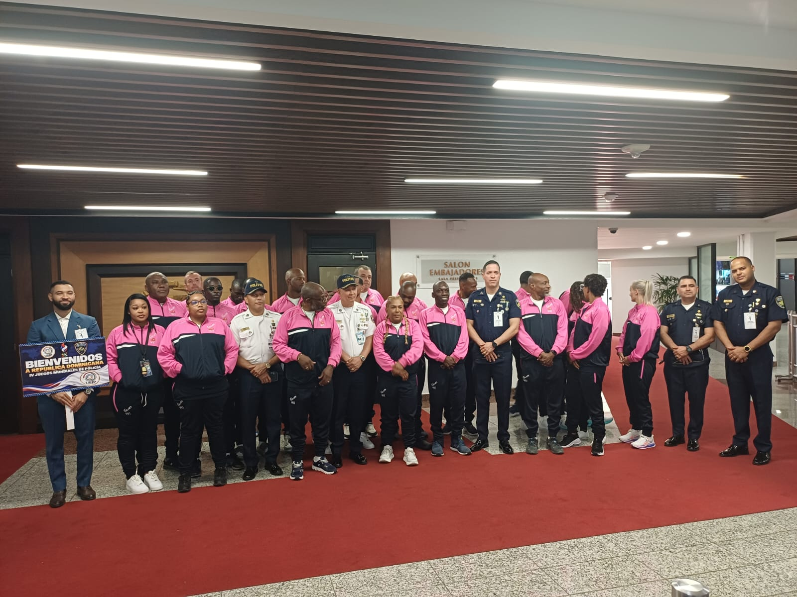 Grupo de atletas con uniformes deportivos rosados durante la recepción.