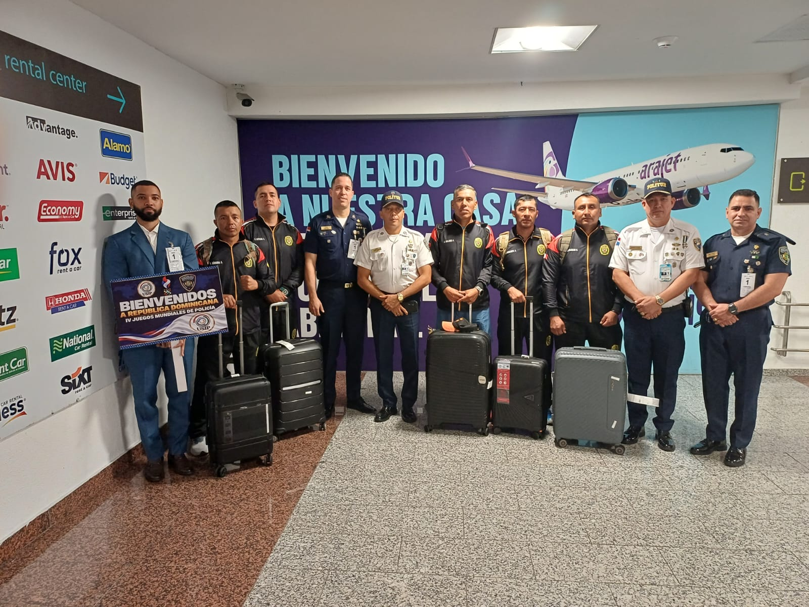 Delegación reunida ante un panel de bienvenida en el aeropuerto.