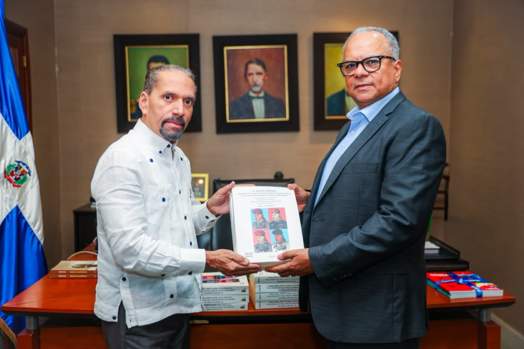 Juan Pablo Uribe entrega un ejemplar de Ajusticiamiento de Trujillo a un representante de UNAPEC.