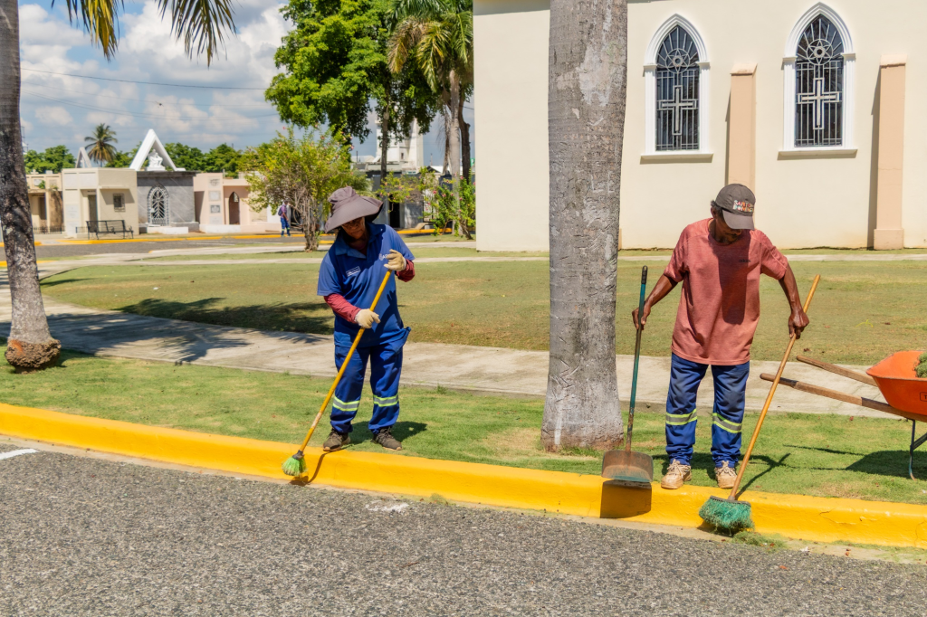 Trabajadores municipales barren y limpian los alrededores de un cementerio