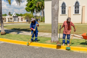 Trabajadores municipales barren y limpian los alrededores de un cementerio