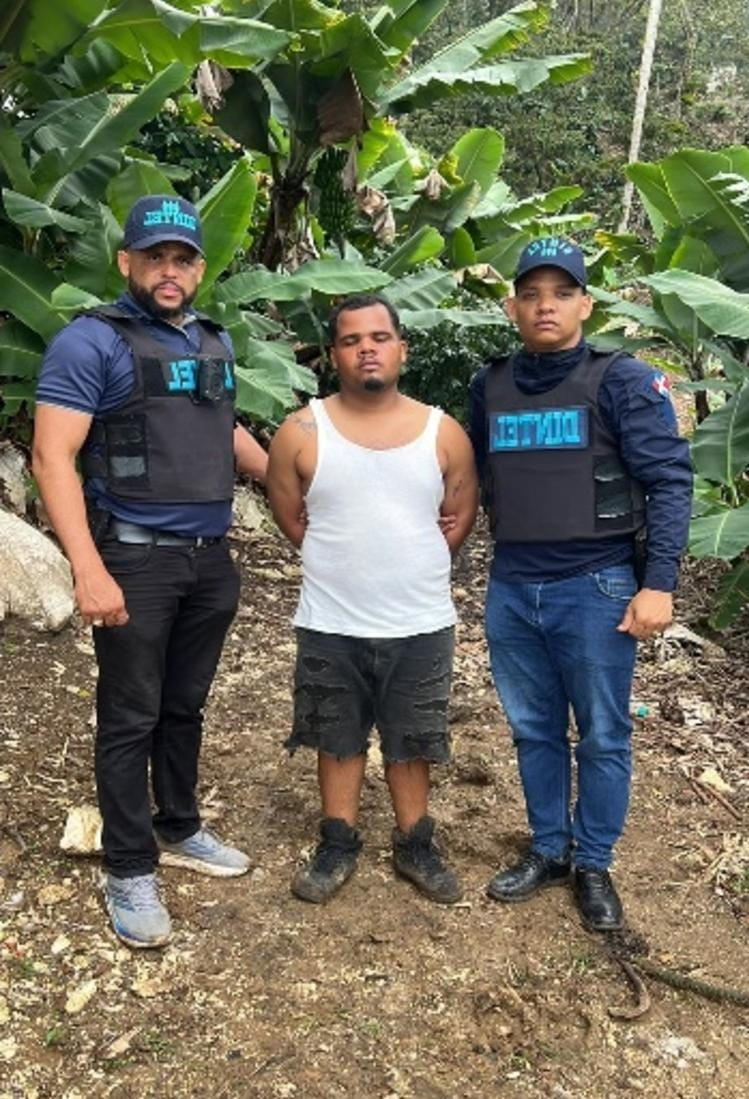 Hombre detenido junto a dos agentes policiales en una zona de vegetación